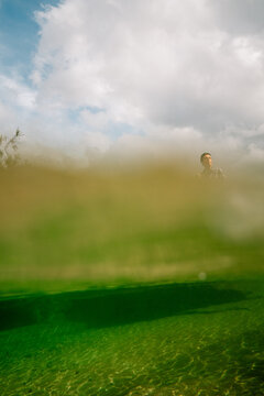 Man Standing Near a Greenish Water Body Under Cloudy Skies