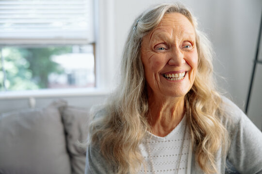 Smiling woman sitting in a cozy living room with natural expression