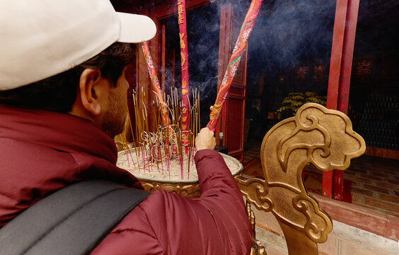 Man lighting incense sticks at temple in Hanoi Vietnam