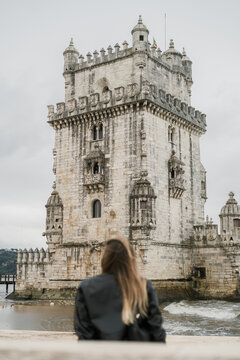 Young woman sitting with her back facing the Bel&eacute;m Tower in Lisbon