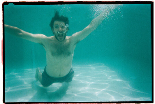 Man swimming underwater with open arms