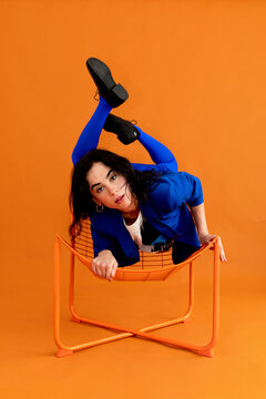 Flexible woman contortionist posing on chair 