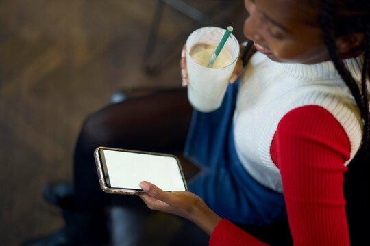 Young Woman Interacting With Smartphone While Enjoying a Drink