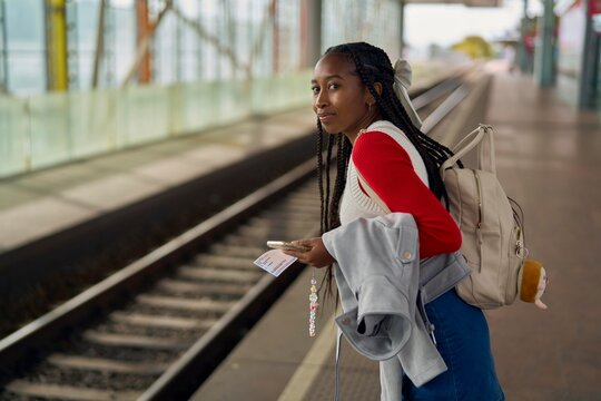 Woman Waiting at a Train Station While Holding a Ticket