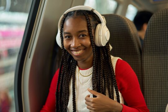 Smiling Woman Enjoying Music on Public Transport in Urban Setting