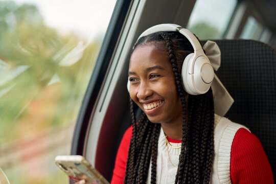 Young Girl Enjoys Music on a Train Journey Through Nature