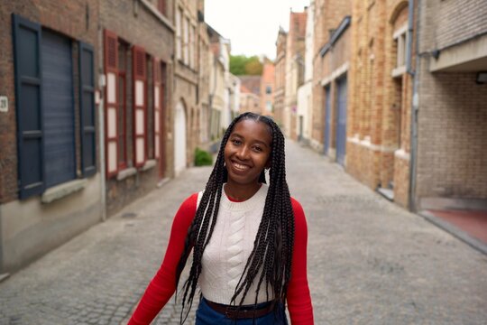 Young Woman Smiling in Charming Cobblestone Alley in Fall
