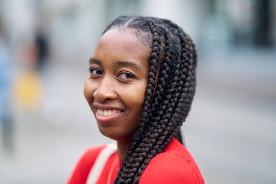 Smiling Woman With Braided Hair Enjoys a Sunny Day Outdoors