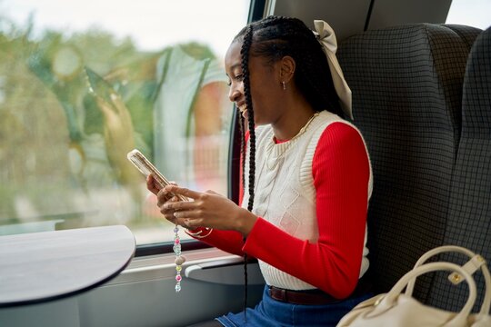 Young Woman Enjoys a Train Journey While Using Her Smartphone