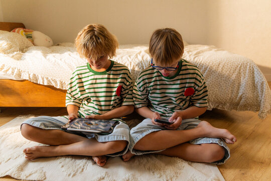 Two boys use gadgets at home