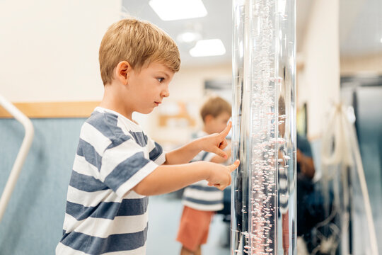Child exploring sensory bubble tube during pediatric therapy