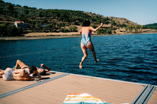 Enjoying a Sunny Summer Day by the Lake With Friends Jumping in Water