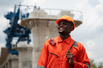 The survey team is operating a theodolite while referencing road construction plans. Civil engineers are taking measurements with surveying equipment at the construction site.