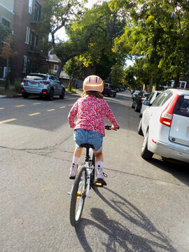 A child wearing a helmet and bright patterned shirt rides a bicycle