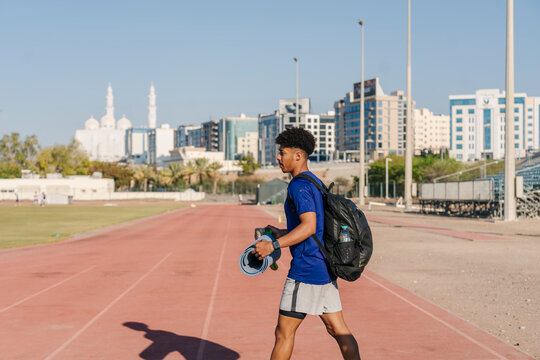 Young male athlete walking on running track in Muscat, Oman