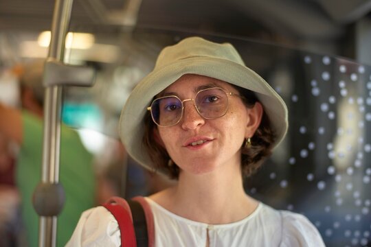 Smiling Woman With Glasses and Hat in a Crowded Bus Setting