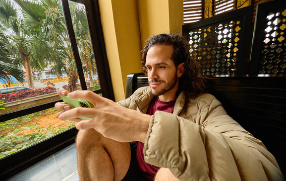 Man holding smartphone while seated near window in Vietnam