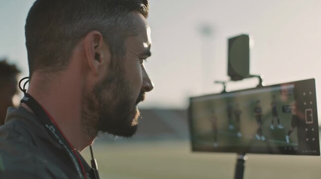 Focused coach watching game on field with blurred stadium background