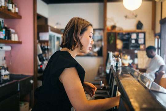 A woman working behind a bar in a cozy Japanese bar