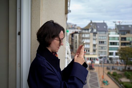 Young Woman Capturing City Views From a Balcony in Cloudy Weather