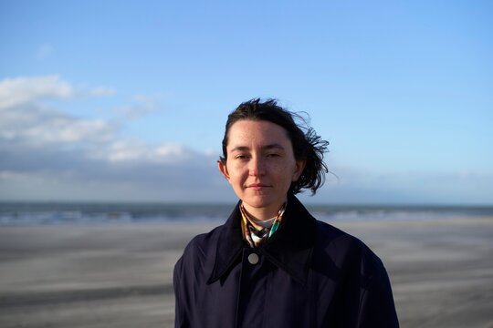 Young Woman Standing on the Beach With Wind in Her Hair