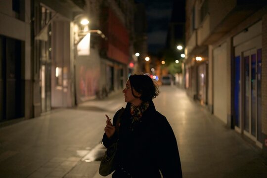 Woman Walking Alone in a Quiet City Street at Night