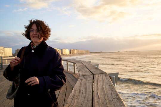 Woman Enjoying Sunset on a Pier by the Ocean in a Coastal City