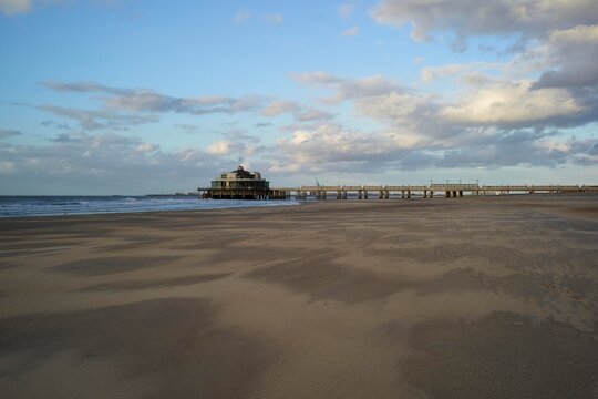 Beach Pier at Sunset With Clouds and Gentle Waves in the Background