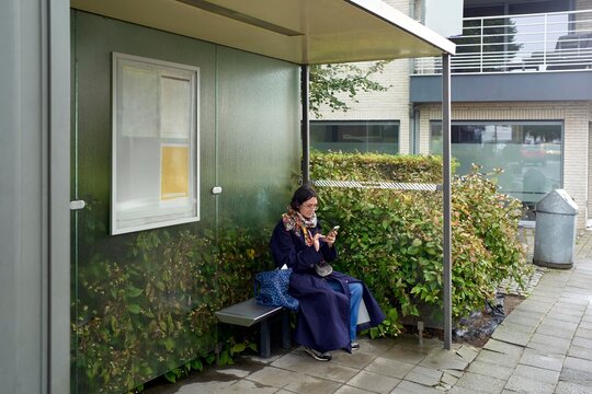 Woman Waiting at a Modern Bus Stop Surrounded by Greenery