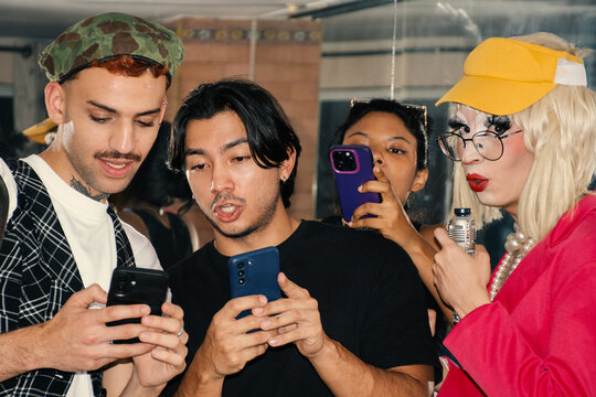 Friends sharing laughter while using smartphones in a lively setting