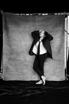 Barefoot woman in oversized suit striking dramatic pose