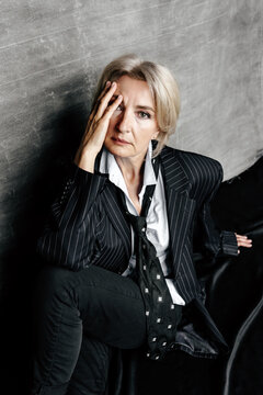 Stylish woman in oversized pinstripe suit with hand on face