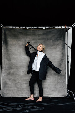 Joyful woman playfully pulling tie in oversized suit