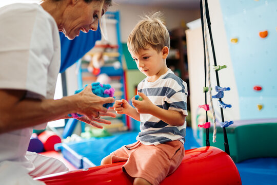 Physiotherapist helping child with psychomotor toy during therapy