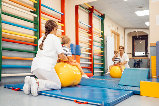 Physiotherapist assisting child with balance exercises on peanut ball
