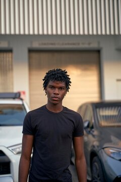 Young Man Stands Confidently in Urban Setting During Daylight