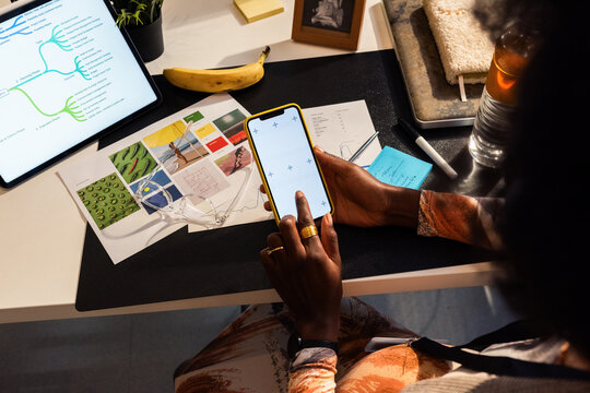 Focused Woman Using Smartphone at her Desk With Notes