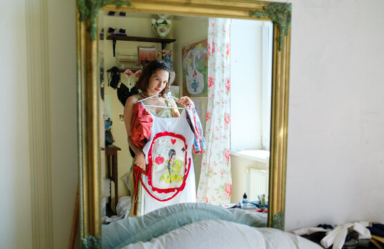a woman tries on a dress in front of a mirror