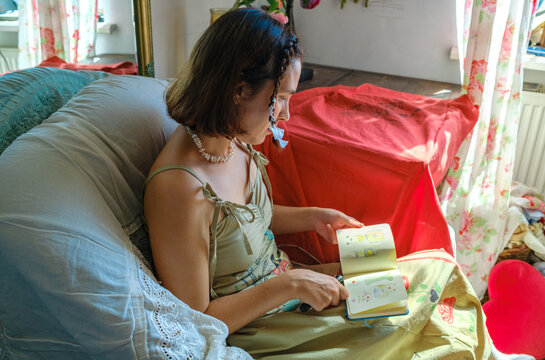 A woman flips through a notebook while sitting in a chair