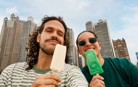 Friends holding popsicles with city buildings