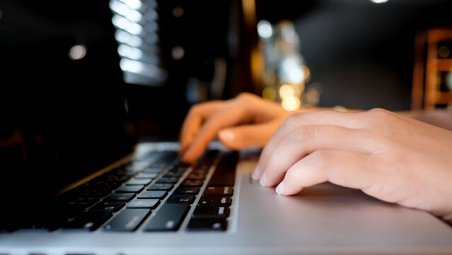Closeup of businesswoman hands typing on laptop keyboard in coffee shop