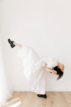 Woman dancing in white dress defying gravity