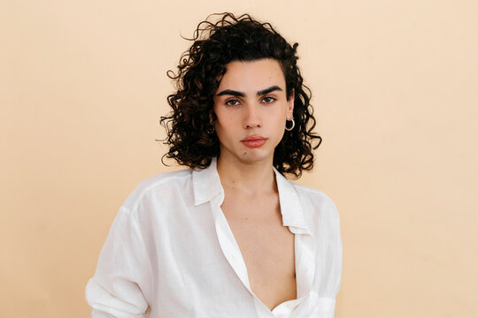 Queer man with curly hair wearing white shirt