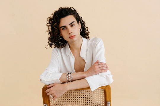 Queer man posing in  with beige background