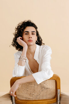 Queer man posing on chair with jewelry