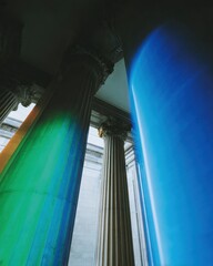 Classic architectural columns of a stone building featuring neon blue and green light leaks for creative documentation and futuristic historical background mockup