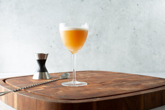 A view of a whiskey sour in a Nick and Nora glass.