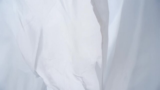 White laundry flapping gently on a clothesline under a clear blue sky with a soft breeze, symbolizing freshness, purity, cleanliness, and a bright