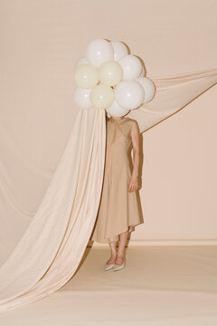 Beige Dress Surrounded By Balloons Conceals Head