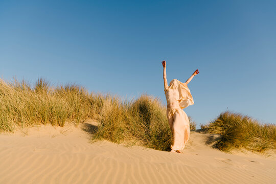 Joyful Person Raising Arms on Sand Dune